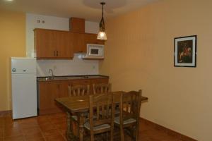 cocina con mesa de madera y nevera blanca en Hotel y apartamentos La Casa Rural, en Chinchón