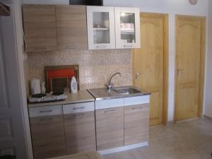 uma cozinha com armários de madeira e um lavatório em Heni Vendégháza em Vadna