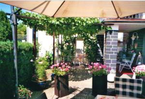 a patio with flowers and an umbrella on a house at Ferienwohnung Büttner in Solms-Oberbiel