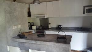 Una cocina con gabinetes blancos y encimera. en La Gringa, un espacio único en el medio del bosque, en Mar de las Pampas 13 fotos más