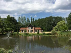 a house next to a lake with trees at Everglades in Denver