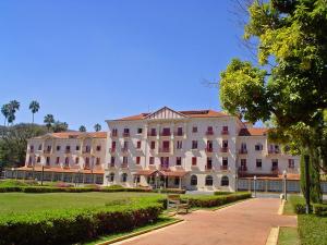 un gran edificio blanco con un parque enfrente en Palace Hotel - Poços de Caldas, en Poços de Caldas