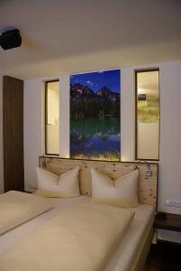 Un dormitorio con una cama con almohadas y una pintura en Appartementhaus Wetterloch, en Lermoos
