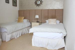 a bedroom with two beds and a mirror on the wall at Laurels Guesthouse in Witney