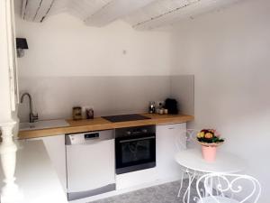 uma cozinha com um balcão, uma mesa e um lavatório em La Grange aux Coqs em Ittenheim