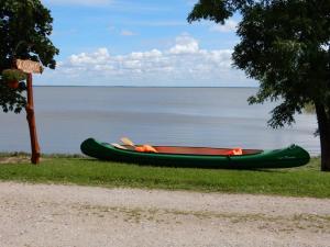 a green canoe sitting on the grass next to the water at Kalda Camping Valma in Valma +10 photos