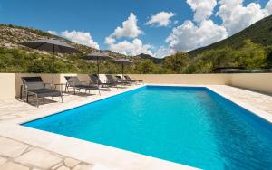 a swimming pool with chairs and umbrellas on a patio at Agrotourism Matusko in Neum