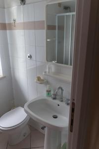 a white bathroom with a toilet and a sink at B&B Apartments Casa Sullavalle in Montefortino