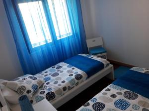 a bedroom with two beds and a window with blue curtains at Apartamento Sado in Setúbal