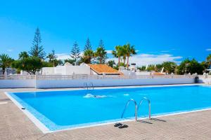 a large blue swimming pool with palm trees in the background at Cozy apartment in Costa del Silencio in Costa Del Silencio