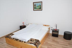 um quarto com uma cama com lençóis brancos e duas mesas de cabeceira em Pensiunea Lavinia em Calvini