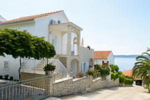 une maison blanche avec une clôture en face de l'eau dans l'établissement Apartments Klasan, à Trogir