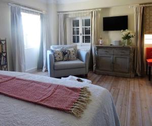 a bedroom with a bed and a chair and a television at Durrell Liston Suites in Corfu