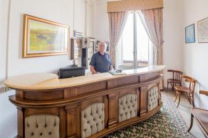 a man standing at a reception desk at Hotel AeR BJ Vittoria in Cagliari