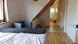 シュクラルスカ・ポレンバにあるDomek nad Złotym Potokiemのベッドルーム1室(ベッド1台、青い椅子、階段付)