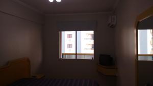 1 dormitorio con ventana, 1 cama y TV en Apartamento Meia Praia, en Itapema