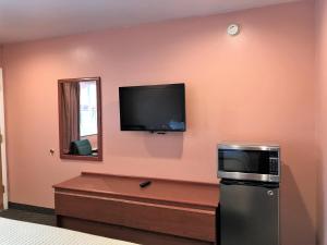 a room with a microwave and a tv on a wall at Bestway Inn in Grants Pass