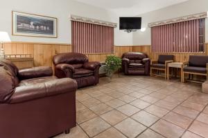 a waiting room with leather furniture and a flat screen tv at AmericInn by Wyndham Eagle River Downtown in Eagle River