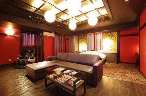 a living room with a couch and a bed at BlueHotel sju(:)pri:m (Adult Only) in Sapporo