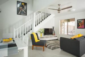 a living room with a staircase with a couch and a table at Byron Central Apartments in Byron Bay
