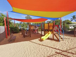 a beach area with chairs, tables, and umbrellas at Discovery Parks - Coolwaters, Yeppoon in Kinka