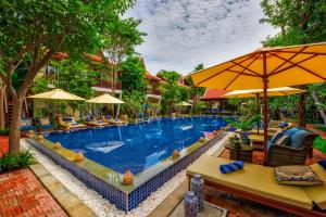 a pool at a resort with chairs and umbrellas at Mane Village Suites in Siem Reap