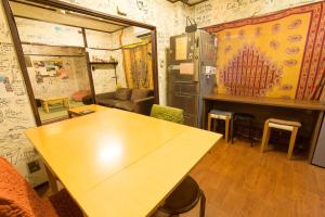 
a room with a table, chairs, and a painting on the wall at Backpackers Hotel Toyo in Osaka
