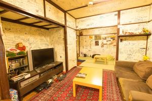 a living room with a couch and a tv at Backpackers Hotel Toyo in Osaka