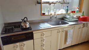 a kitchen with a sink and a stove at Minshuku Suhara in Okuwa
