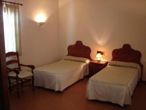 ein Hotelzimmer mit 2 Betten und einem Stuhl in der Unterkunft Villa Turística de Priego in Priego de Córdoba