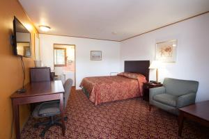 a hotel room with a bed and a desk and a chair at Park Motel in Marshfield