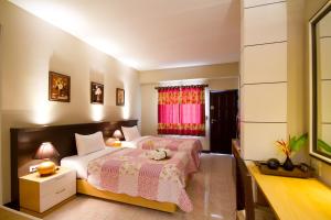 a bedroom with two beds and a desk and a window at Rommai Greenpark in Lampang