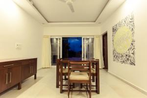 a dining room with a table and chairs and a painting at Crayons Guest House Munnar in Munnar