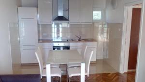 a white kitchen with a white table and chairs at Guest House Silvia in Rab