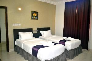 duas camas sentadas num quarto de hotel com cortinas em Gateway Salalah Apartments em Salalah
