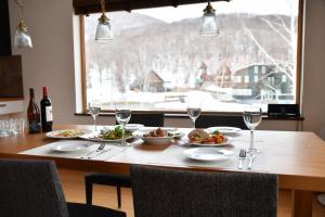 stół z talerzami jedzenia i kieliszkami wina w obiekcie Hana & Jo w mieście Niseko