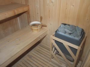 a sauna with a bucket of rocks and a bench at Family Hotel Dalia in Velingrad