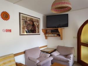 a living room with two chairs and a flat screen tv at Albergo Posta in Colle Santa Lucia