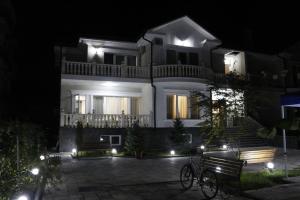 ein weißes Haus in der Nacht mit Bänken und Lichtern in der Unterkunft Guest House Sofia in Kobuleti