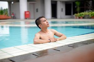 a young man laying in a swimming pool at Midtown Residence Simatupang Jakarta in Jakarta