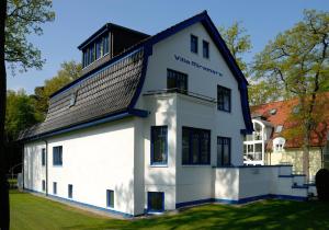 ein weißes Gebäude mit einem schwarzen Dach in der Unterkunft Strandvilla Miramare in Boltenhagen