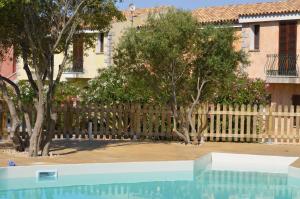 a swimming pool in front of a fence with trees at Residence Costa Del Turchese in Badesi