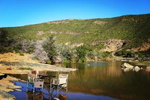 two chairs sitting on the shore of a river at Koedoeskop Private Mountain Reserve in Waterford