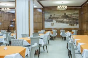 a dining room with tables and chairs and a painting on the wall at Hotel Plaza Viktoria in Gyumri