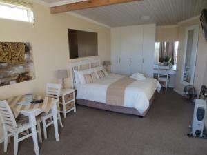 a bedroom with a bed and a table and chairs at Masada Guest House in Langebaan