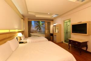 Habitación de hotel con 2 camas y TV de pantalla plana. en Kai Fu Hotel en Taoyuan