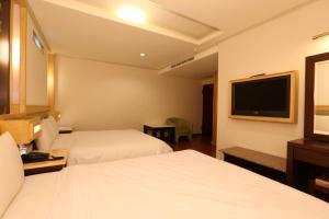 a hotel room with two beds and a flat screen tv at Kai Fu Hotel in Taoyuan