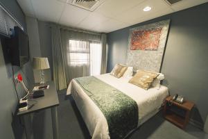 1 dormitorio con cama, mesa y TV en Blue Diamond Boutique Hotel, en Pretoria