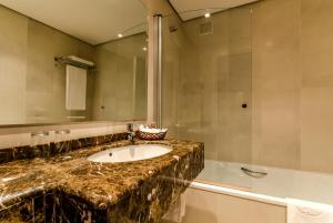 a bathroom with a sink and a mirror and a tub at Hotel Temple Ponferrada in Ponferrada