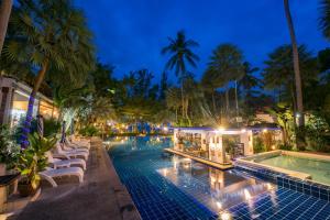 una piscina con tumbonas y un complejo por la noche en Koh Tao Montra Resort, en Ko Tao